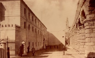Fachada de Día Sanz, 1879-1880. A la izquierda la puerta de carretas flanqueada por dos cañones, y a continuación la de Día Sanz. Al fondo el saliente (parte del patio de Ordenanzas) que desapareció con la alineación de 1926, y la espadaña de la iglesia de San Francisco. 9.- ACADEMIA DE ARTILLERÍA, BIBLIOTECA. FOT. 39-7.